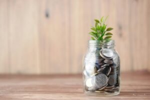 A mason jar filled with coins and a sprouting plant